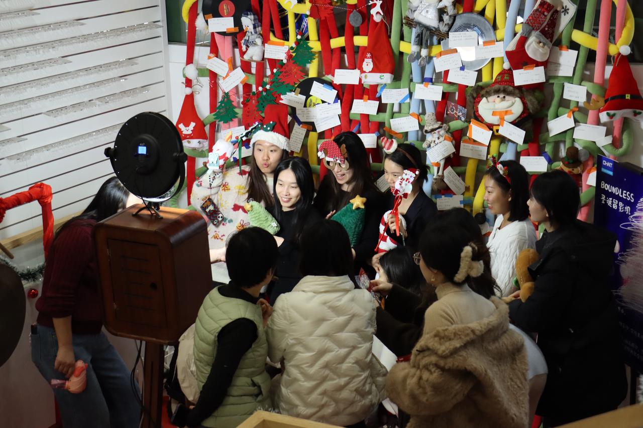 CHINT employees gather at a festive photo booth and wish wall, capturing joyful moments during Christmas celebrations