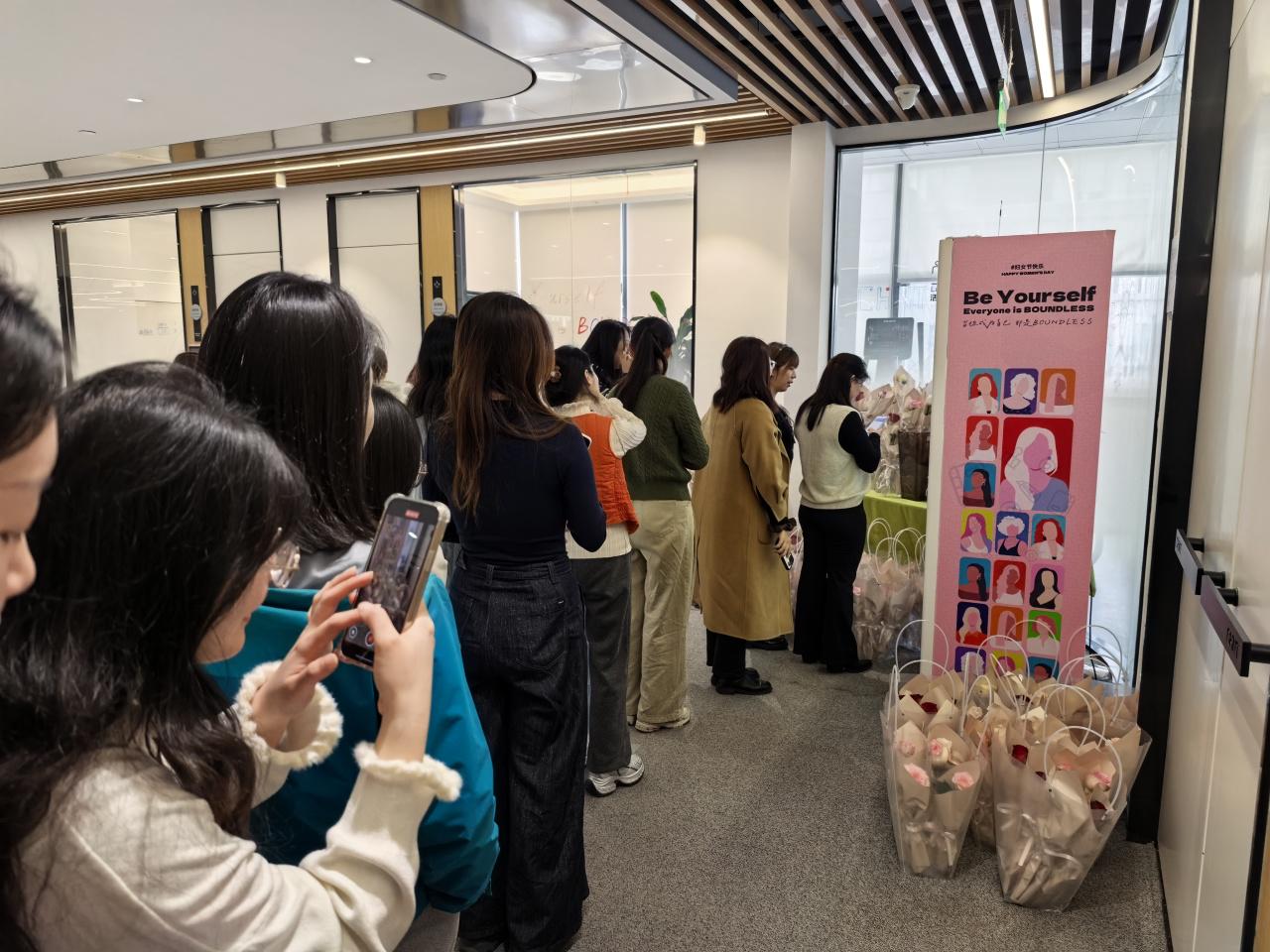 Employees lining up at an office Women’s Day celebration to receive flowers and gifts.