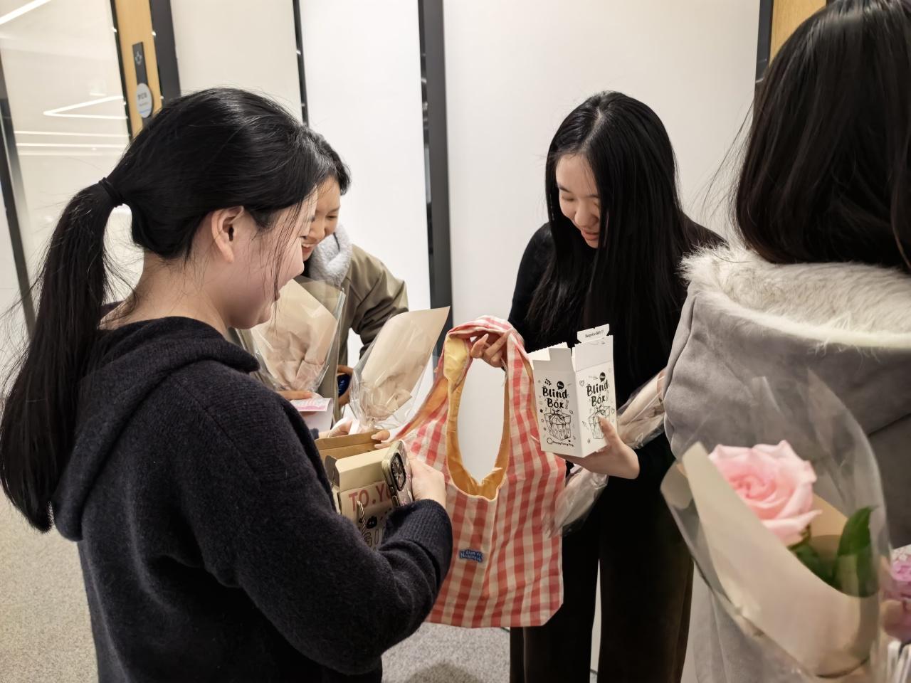 Employees receiving Women’s Day gifts and flower bouquets during an office celebration event.