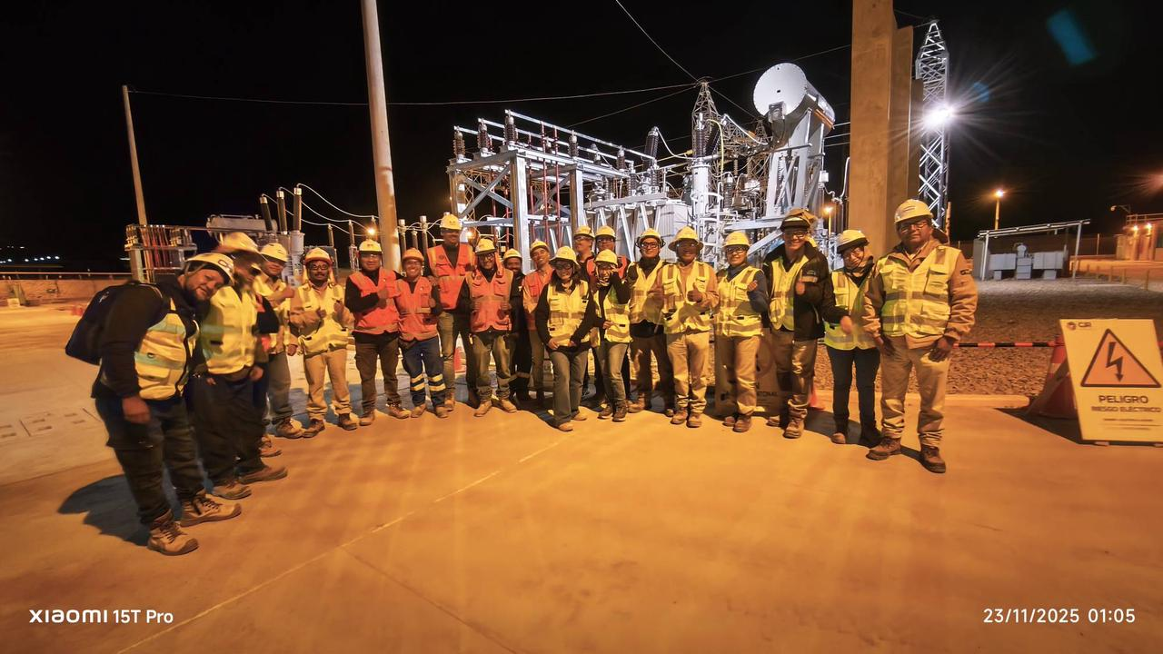 Project team standing in front of a high-voltage substation during nighttime commissioning work
